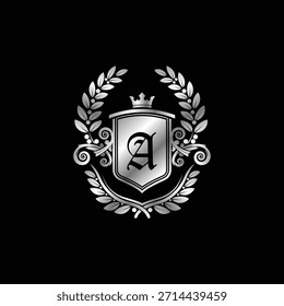 Un sofisticado emblema heráldico plateado que muestra un escudo adornado con una corona, una antigua letra gótica A, enmarcada por elegantes coronas de laurel.