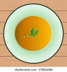 Soup with pumpkin. Plate stands on a wooden surface. Top view.