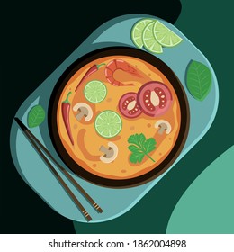 Soup Tom Yam on a tray with chopsticks and leafs