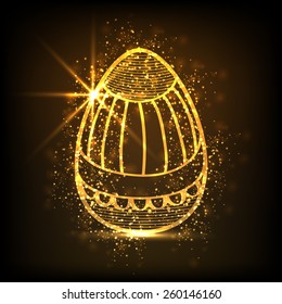 Sparkling golden Easter egg decorated with floral design on brown background.