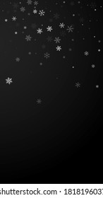 Sparse snowfall Christmas background. Subtle flying snow flakes and stars on black background. Appealing winter silver snowflake overlay template. Ideal vertical illustration.