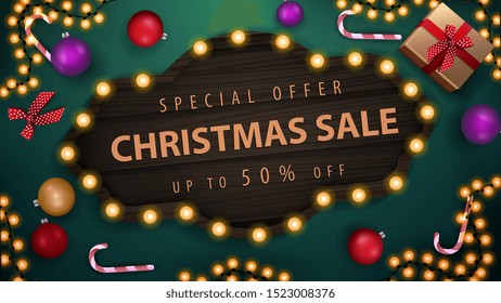 Special offer, Christmas sale, up to 50% off, green discount banner with Christmas balls, candy canes, garland and gifts, top view