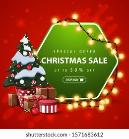 Special offer, Christmas sale, up to 50% off, square red and green banner with hexagonal sign wrapped garland and Christmas tree in a pot with gifts