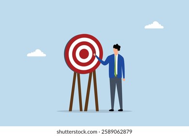 Specific goal, businessman pointing at center of bullseye archery target.