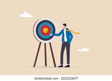 Specific goal, clarify objective or target, focus or concentrate on purpose to win business mission, perfection or aiming at target concept, businessman pointing at center of bullseye archery target.