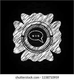 speech bubble icon inside chalkboard emblem on black board