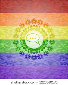 speech bubble icon inside emblem on mosaic background with the colors of the LGBT flag