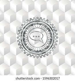 speech bubble icon inside grey emblem with geometric cube white background