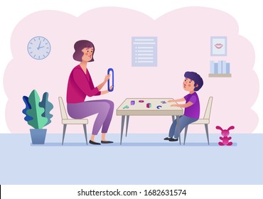 Speech therapist sits at a table with a boy and teaches him the sound "O"