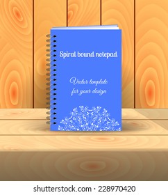 Spiral bound notepad. Vector template. Easy to place your image on the cover. Presentation on the wooden background. Can be use for business design.