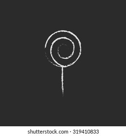 Spiral lollipop hand drawn in chalk on a blackboard vector white icon isolated on a black background.