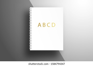 A spiral notebook with gold letters ABSD is on the surface with a diagonal separator. Realistic template for corporate branding