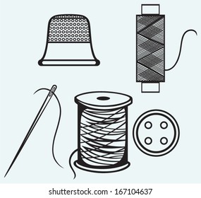 Spool with threads, sewing button and thimble isolated on blue background