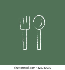 Spoon and fork hand drawn in chalk on a blackboard vector white icon isolated on a green background.
