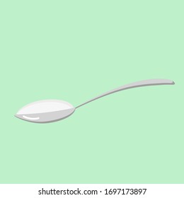 Spoon with white powder on a light green background.