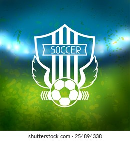 Sports label with soccer symbols on blurred stadium background.