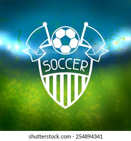 Sports label with soccer symbols on blurred stadium background.