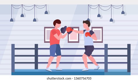 sportsman boxer practicing boxing exercises with male trainer man fighter in red gloves exercising fight ring arena interior healthy lifestyle concept flat horizontal