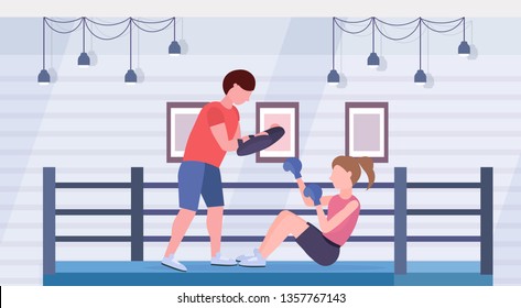 sportswoman boxer doing boxing exercises with personal trainer girl fighter in blue gloves working out on floor fight club ring arena interior healthy lifestyle concept