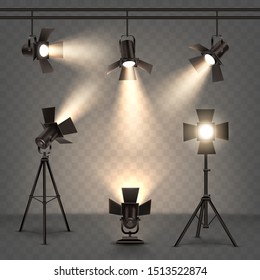 Spotlights realistic vector set. Professional photo and video lamps, hanging and standing on tripod, stage equipment with warm yellow light on transparent background.