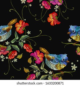 Spring art. Embroidery seamless pattern. Funny little blue birds and wild red roses. Fashion template for clothes, textiles, t-shirt design