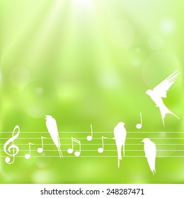 Spring background with notes and birds on a  blurred  green background