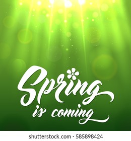 SPRING IS COMING Hand lettered style spring background. Handmade vector calligraphy on abstract glowing green background with  bokeh light and sun beams