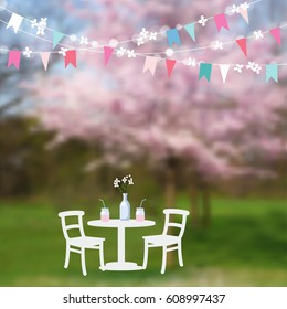 Spring garden party. Table with drinks and paper flags decoration. Modern blurred background with blossoming Japanese cherry trees. Vector illustration background.