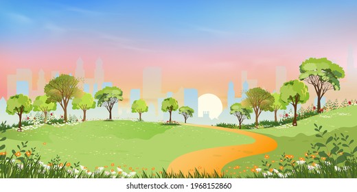 Spring landscape at city park in the morning, Natural public park with flowers blooming in the garden, Peaceful scene of green fields with blurry cityscape building, cloudy and sun on summer