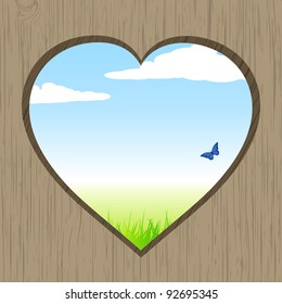 Spring landscape viewed through a heart shaped hole on wood