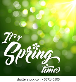 IT'S SPRING TIME Hand lettered style spring background. Handmade vector calligraphy on abstract glowing green background with bokeh light and sun beams