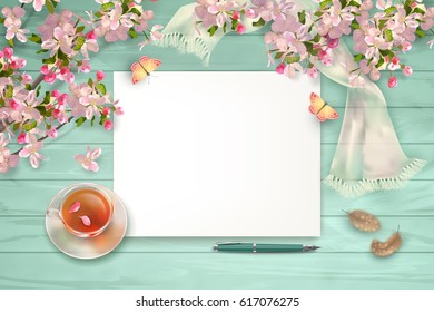 Spring top view background with blank sheets of paper, blossoming tree branches, feathers, glass teacup and butterfly
