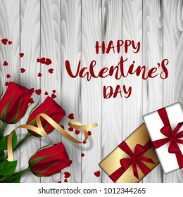 A square light wooden board with red buds of roses on a green stem and a box with a bow, hearts. Festive inscription of the lettering "Happy Valentine's Day" Vector. View from above
