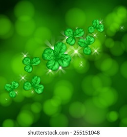 St. Patrick day card. Clovers and lights on green bokeh background.