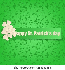  St. Patrick day card. Green paper label and three white paper clovers on green background with clovers.