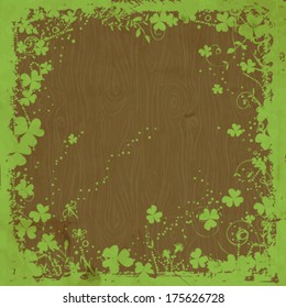 St. Patrick day card, grunge green floral frame with clovers on wooden background with old paper texture