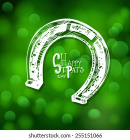  St. Patrick day card, hand- drawn horseshoe and lettering on green bokeh background.