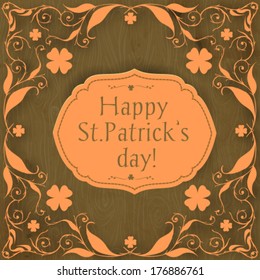  St. Patrick's day card, orange paper floral frame with clovers and label on hand -drawn wooden background  