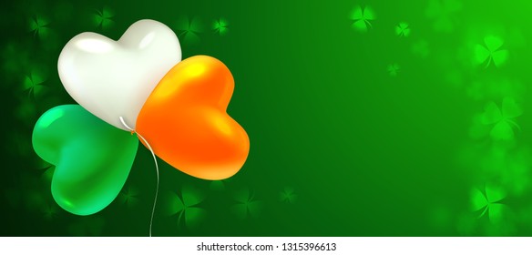 St Patrick's Day. Glossy heart-shaped balloons painted in the colors of the Irish flag. Blurred background with leaves of shamrock. Nice background for greeting card, banner, poster or flyer.