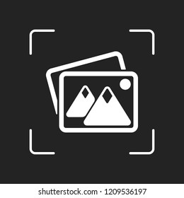 Stack of pictures with couple of mountains and sun. Simple icon. White object in camera autofocus on dark background