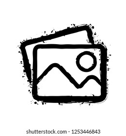 Stack of pictures with couple of mountains and sun. Simple linear icon. Black ink with splashes on white background