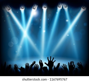 A stage with spotlights at a party or concert with a crowd of peoples hands in silhouette