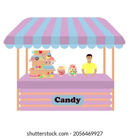 Stall counter with candy, lollipops, macaroons, cupcakes, donuts. Male seller is standing behind the counter.