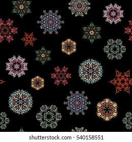 Starry Sky. Falling snow. Seamless texture with green, pink and neutral snowflakes and dots on a black background.