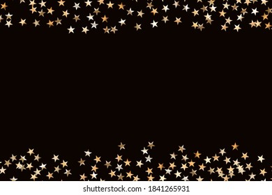 Stars golden glitter confetti isolated on blurred abstract black background. Festive holiday background. Celebration concept. Falling magic gold  particles. Invitation mock up. Top view, flat lay.