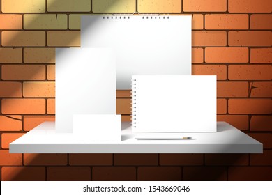 Stationery Set For Branding On White Shelf About The Red Brick Wall. Calendar, Album, Notebook, Business Card And Pencil. Mockup For Design With A Shadows