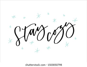 Stay cozy winter quote hand lettering with snowflakes. Modern calligraphy and snow white card template design. Black and blue greeting card, holiday wall art.