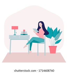 Stay home concept.Young woman sitting on a chair at home and surfing on internet,shopping online using her 
tablet in period of self isolation and social distancing during Covid-19 epidemic.