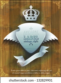steel badge with wings and crown on  wooden background