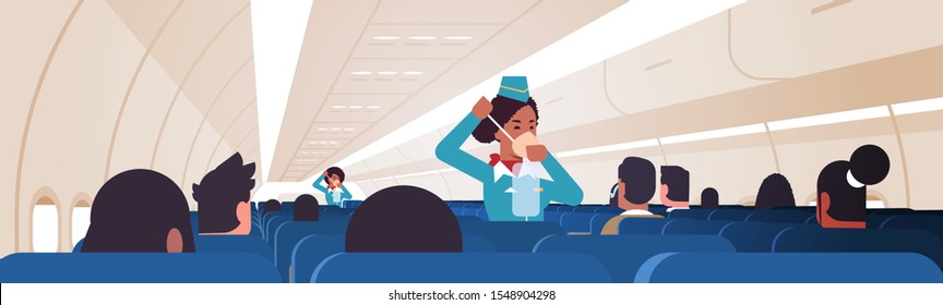 Stewardess Explaining For Passengers How To Use Oxygen Mask In Emergency Situation African American Flight Attendants Safety Demonstration Concept Modern Airplane Board Interior Horizontal Vector